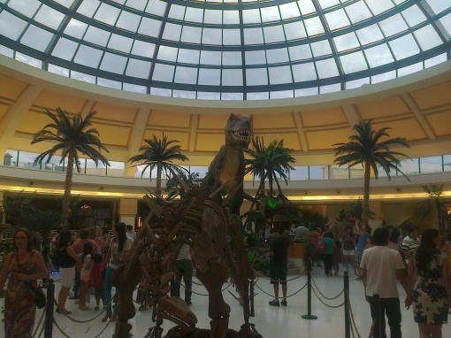 O esqueleto de um stegossauro e, ao fundo, a atração principal da exposição: a réplica de 7 metros do Tiranossauro Rex!